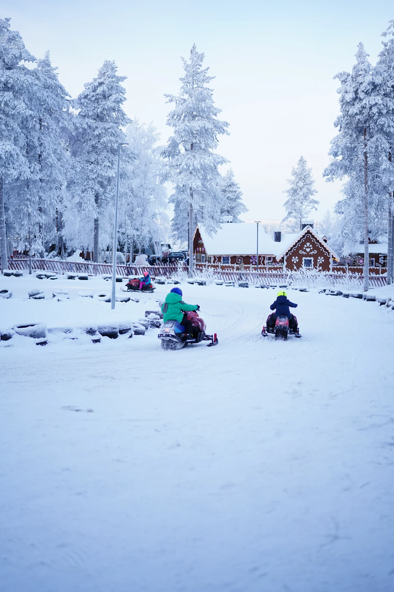 Children riding mini snowmobiles around a supervised snowy circuit