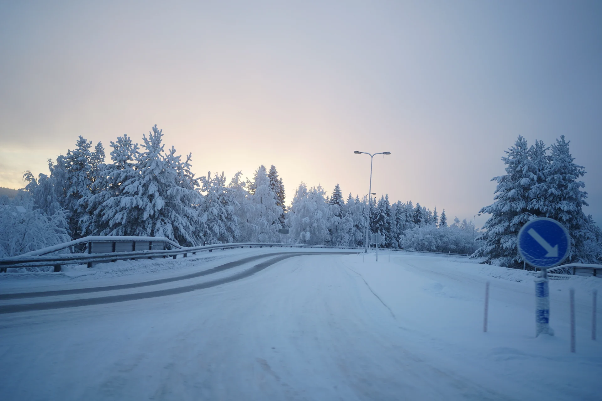 Snow-covered road curving through frost-coated trees near Rovaniemi